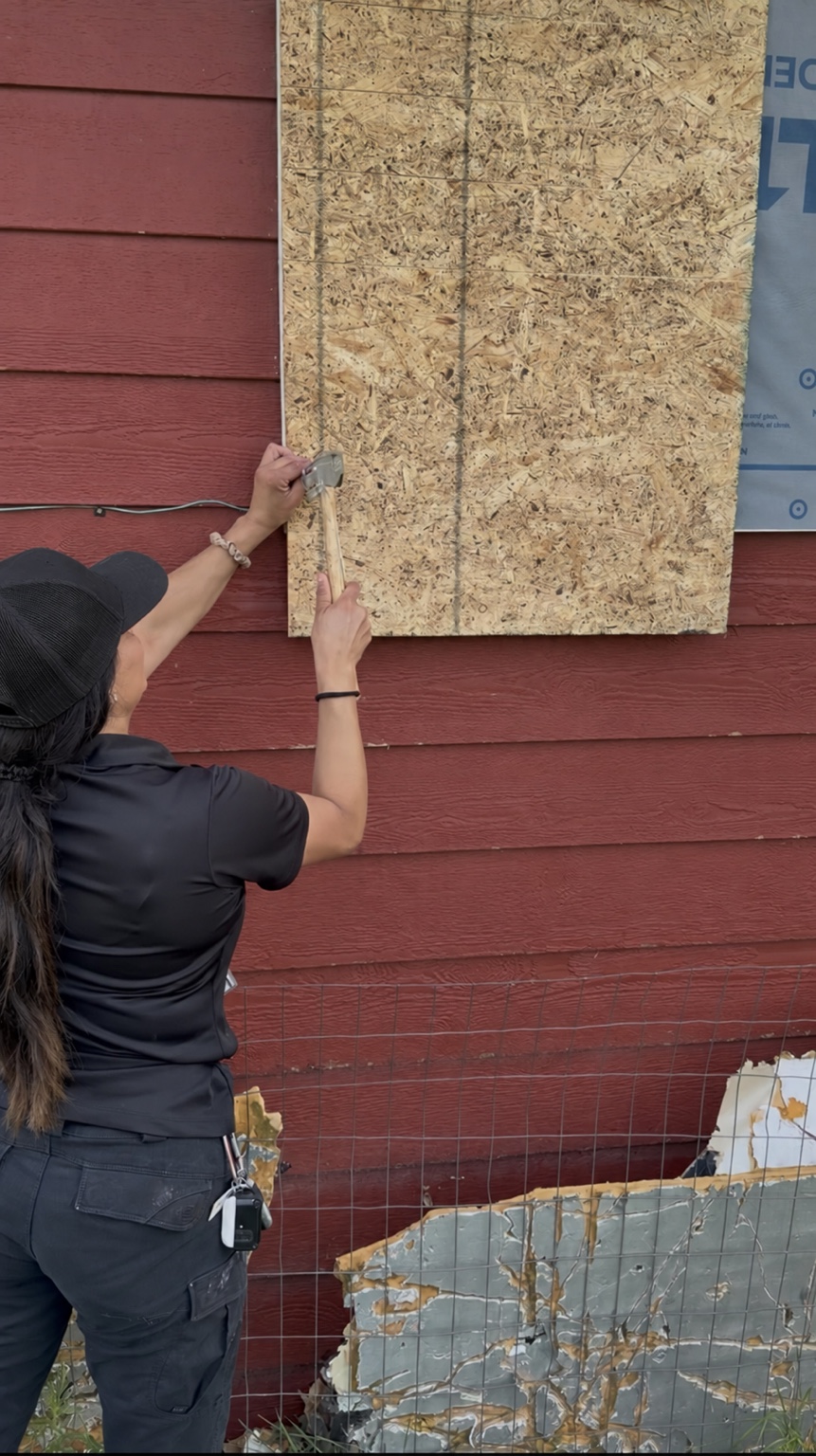 Lori securing temporary plywood boarding over a damaged exterior opening