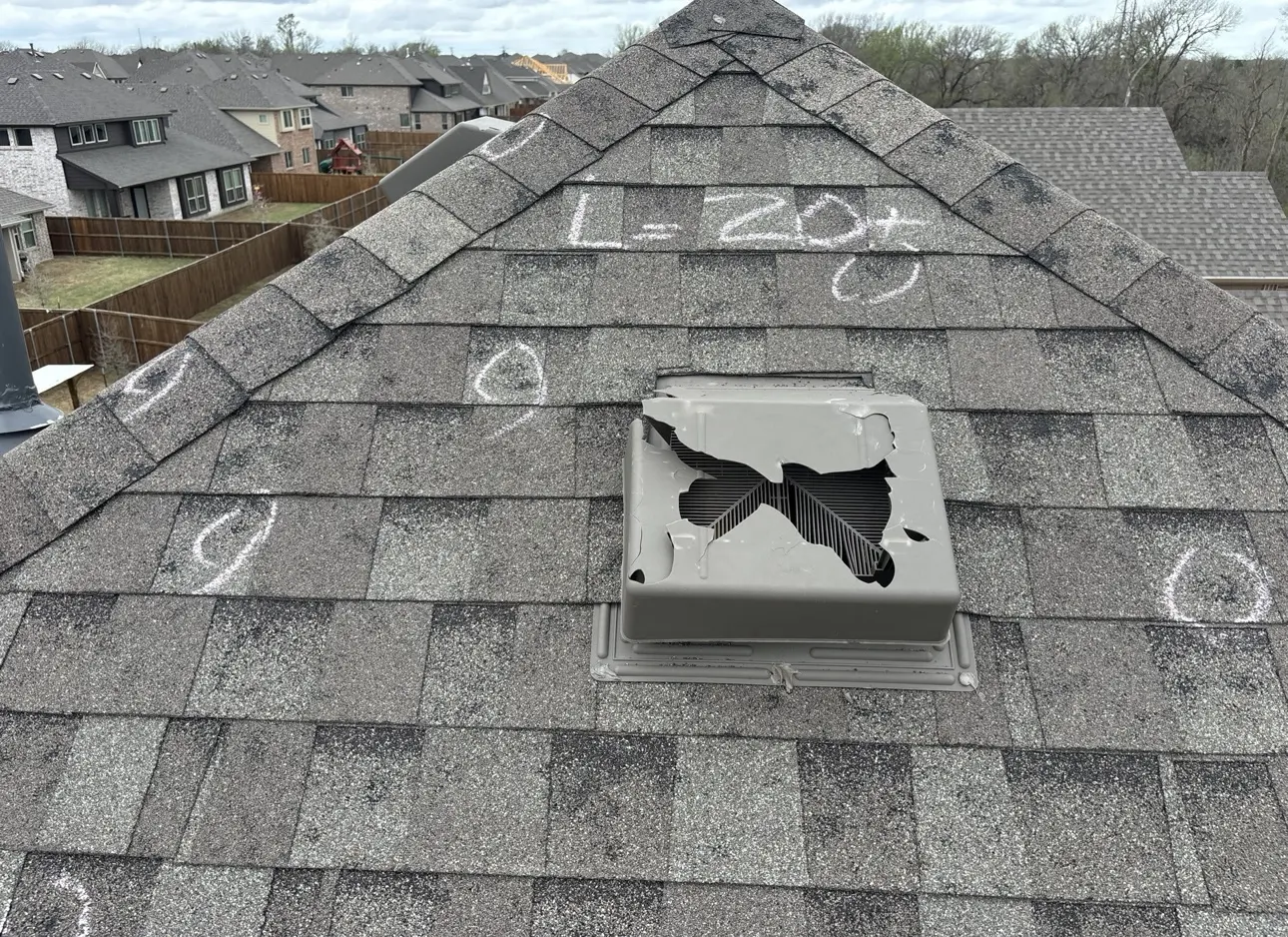 Storm-damaged roof vent surrounded by marked asphalt shingles