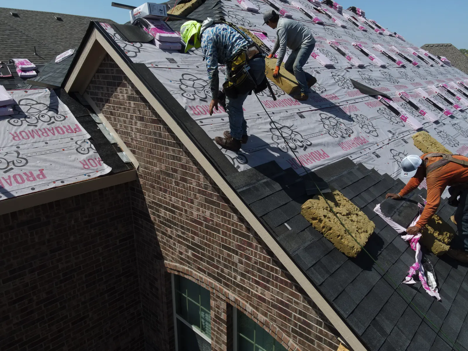 Roofing crew installing shingles and underlayment at the Fort Worth project