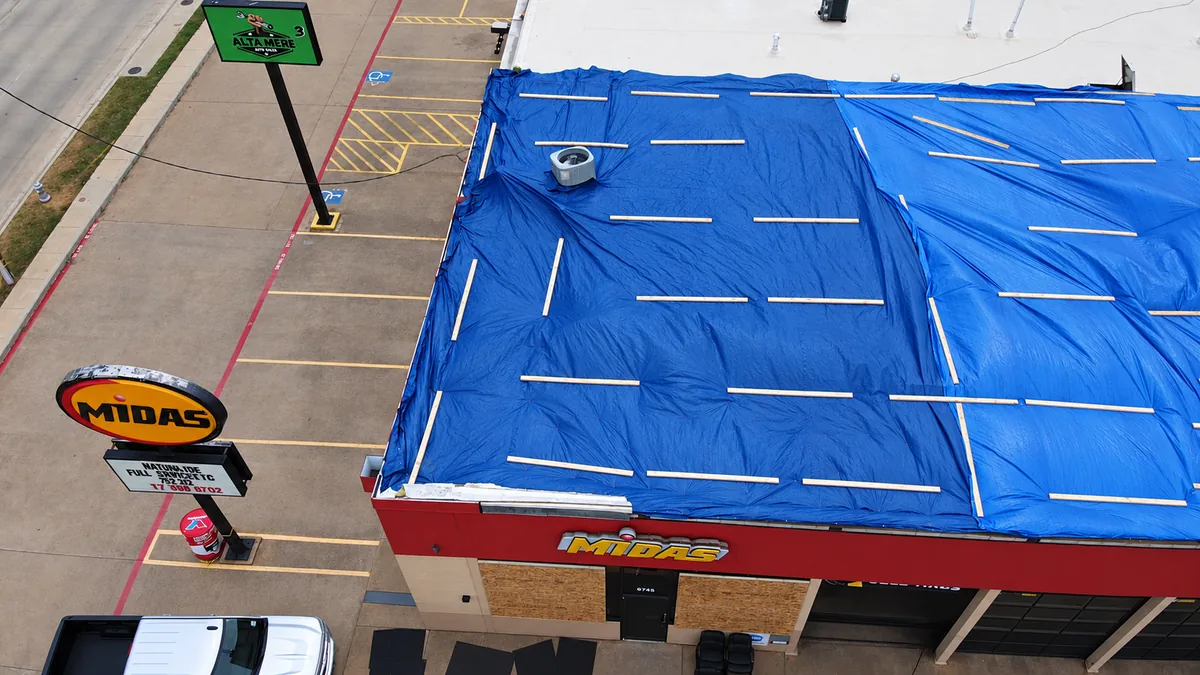 Temporary roof tarping installed over a damaged commercial building roof