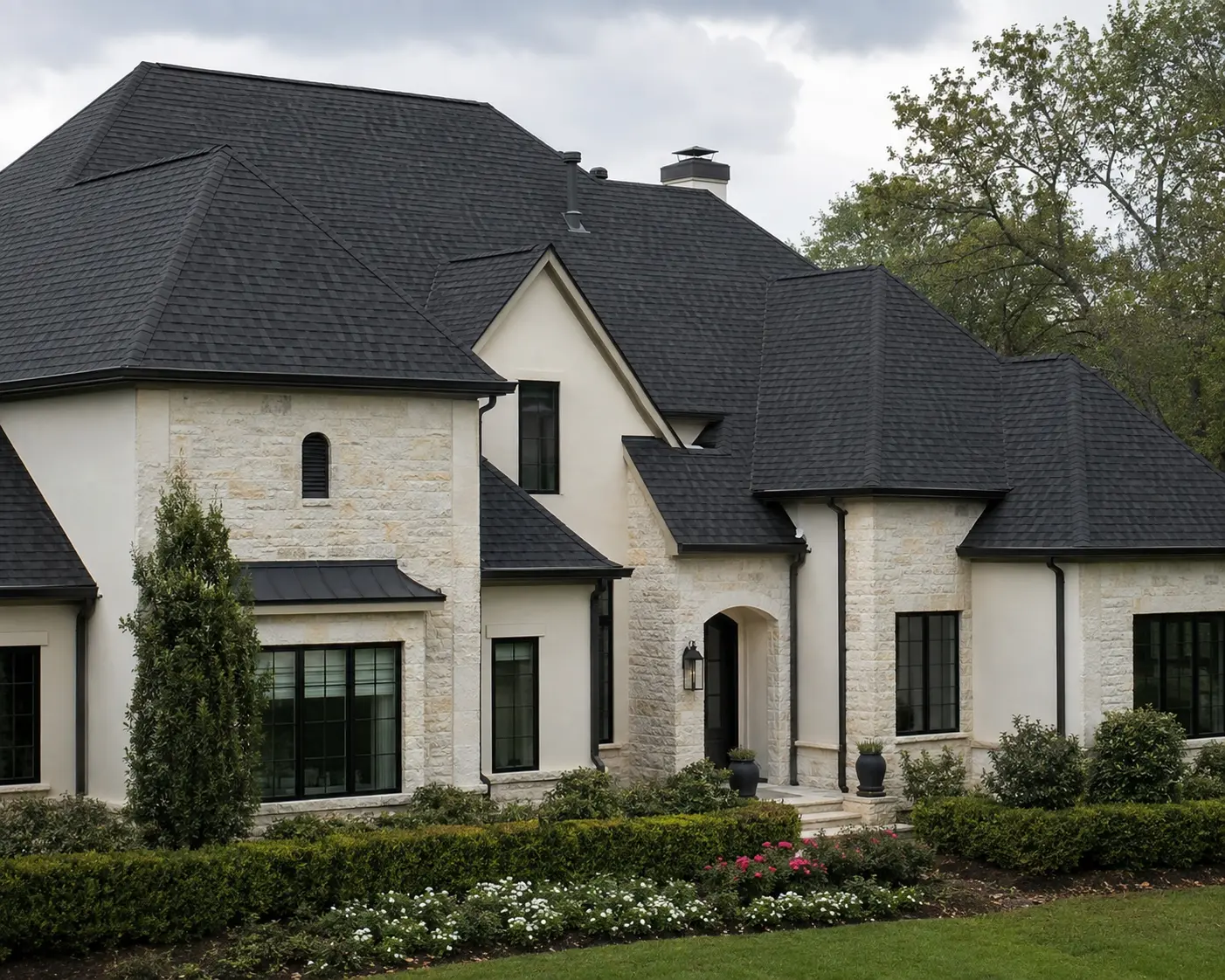 Black architectural asphalt-shingle roof on a light stone residence