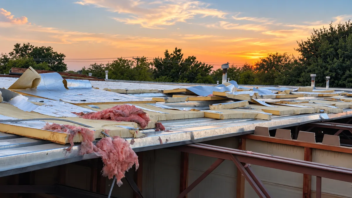Storm damage to a commercial roof, with roofing panels and insulation torn away